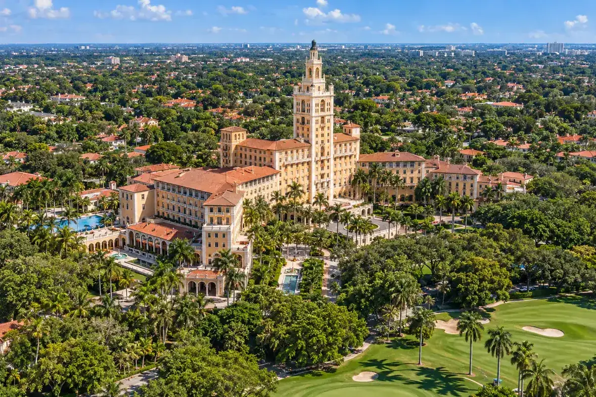 Aerial view of a hotel tower, landscaped grounds and golf course in Coral Gables, Florida